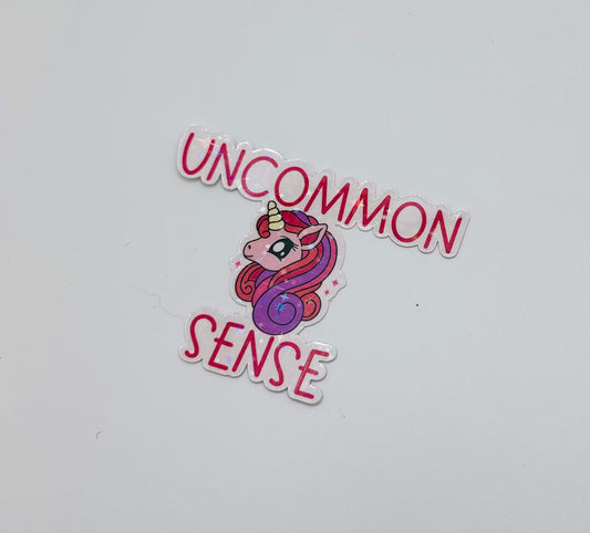 holographic sticker with stars.  Pink and purple unicorn on a light pink background with the words "uncommon sense" in pink writing